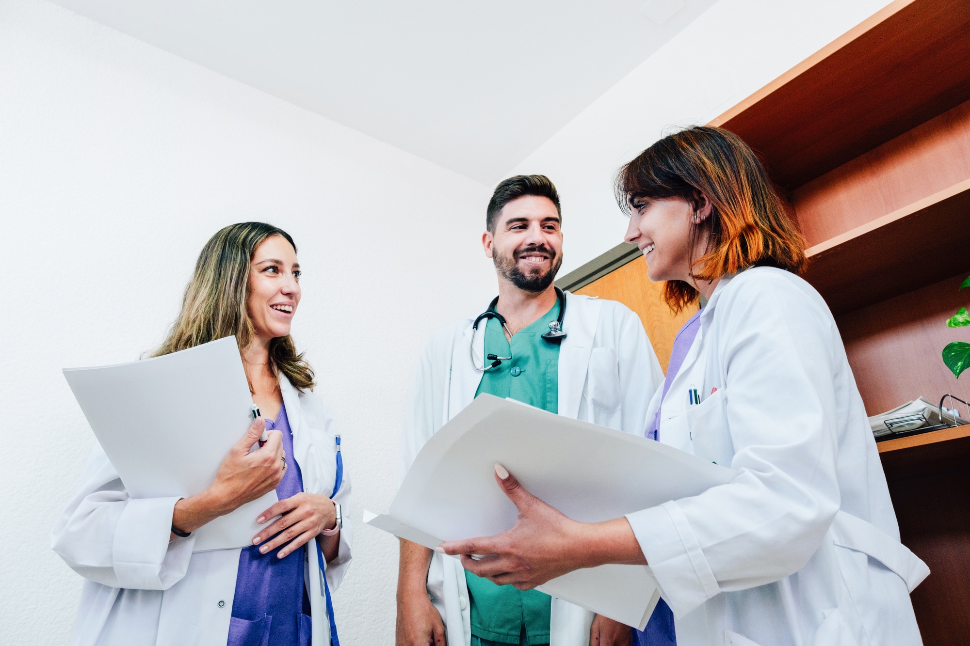 Three happy doctors talk and teamwork in a hospital